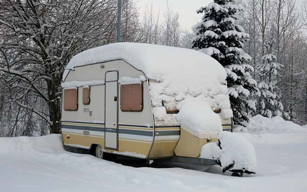 an rv in winter storage covered in snow
