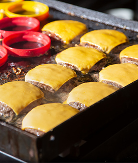 burgers with melted cheese on the griddle