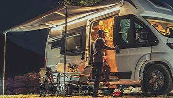Person standing outside camper van at night