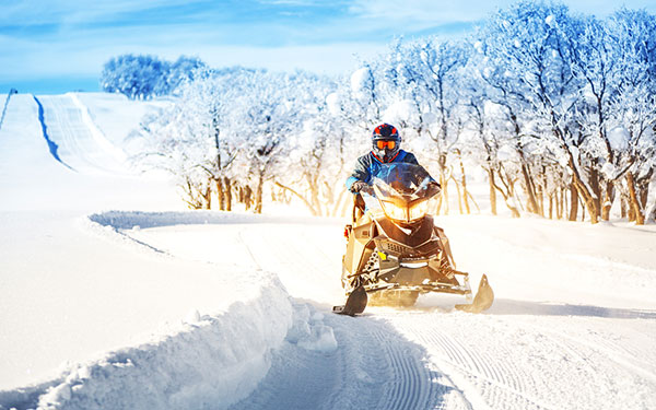 Person snowmobiling on a trail.