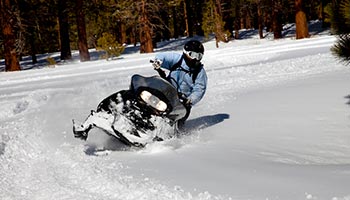 person snowmobiling on a trail turning. 
