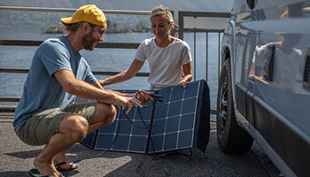 Image of a couple setting up a portable solar panel which is an rv accessory. 