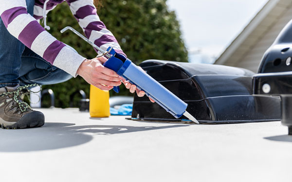 person applying a sealant on their RV to prevent water damage