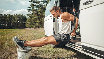 young man exercising outside of their van with bands