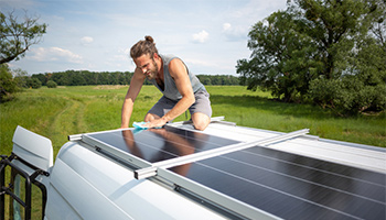 Person on top of their rig cleaning their RV solar panels