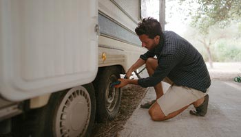 a person working to dewinterize their RV by checking their tires