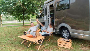 a family sitting outside of their RV enjoying lunch