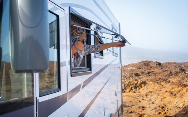 person opening the window to their RV during the day