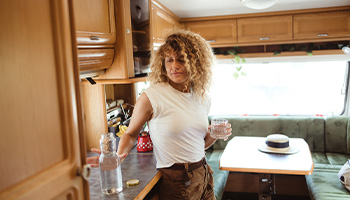 a woman inside of her motorhome pouring a glass of water