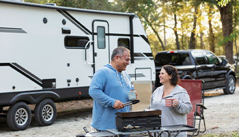 a couple grilling outside of their RV